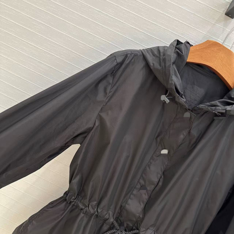 Kapuljačom pamučna windbreaker jakna s UV zaštitom, rezanim rubom i vezom u struku; podstava od pamuka, duljina 50–65 cm