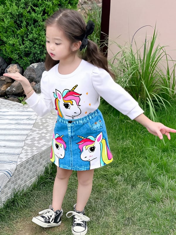Két darabos gyermek szett: hosszú ujjú felső kereknyakú és unikornis mintával és mű denim szoknya; poliészter 95%; 3–8 éveseknek; tavasz 2025.