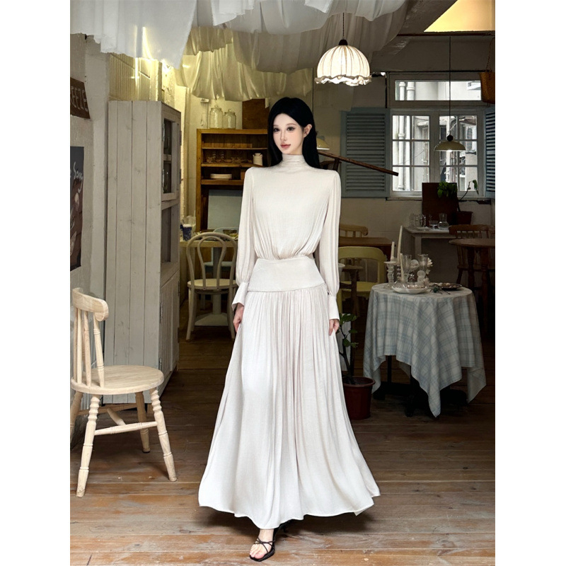 Дълга плисирана рокля от френски сатен, с дълги ръкави, кръгъл деколте и висока талия.