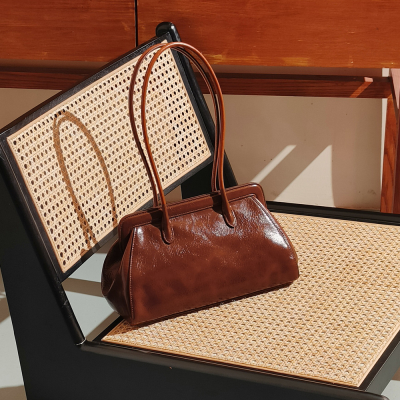 Pažastinė rankinė – natūralios odos iš pirmojo sluoksnio, horizontali kvadratinė forma, magnetinis užsegimas, vidiniai kišenės telefonui ir asmens tapatybės kortelei, miesto minimalistinis stilius