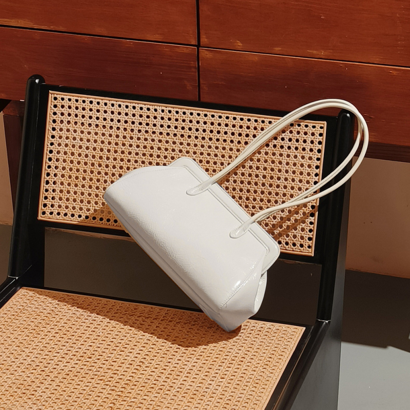 Pažastinė rankinė – natūralios odos iš pirmojo sluoksnio, horizontali kvadratinė forma, magnetinis užsegimas, vidiniai kišenės telefonui ir asmens tapatybės kortelei, miesto minimalistinis stilius