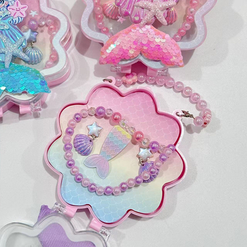 Meitenēm paredzēts jūras sirēnas astes un jūras gliemežu motīvs – kaklarota, gredzens un matu klipsi – materiāls PC – vecums 3–10 gadi – rudens 2025 izdevums