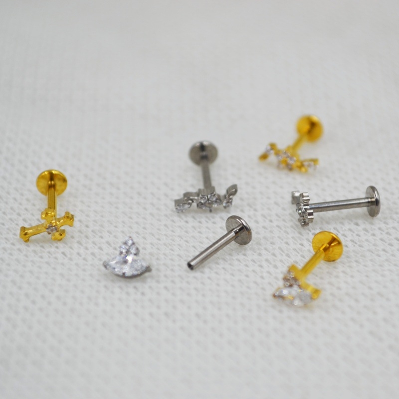 Lūpų piercing papuošalas – titano lydinys, G23 ASTM F136, geometrinis dizainas su gėlės kryžiumi ir marquise cirkoniu, graviruotas