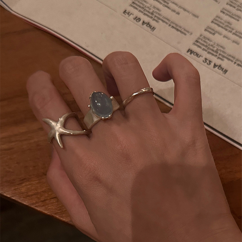 Nyitott geometriájú gyűrű matt felületű ötvözetből, tengeri csillag és macskaszem díszítéssel, elektroplatírozott