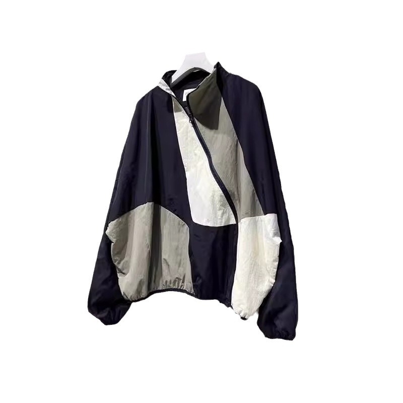 Ženska windbreaker jakna s dijagonalnim plaktom i kontrastnim šavovima, slobodan kroj, srednja duljina, polu-visoki ovratnik, dugi rukavi, poliester 70–80%