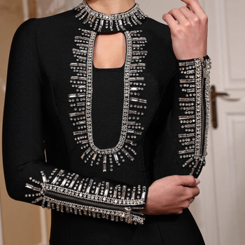 Duga večernja haljina s dugim rukavima, uski kroj, ukrašena perlicama i zatvaračem, materijal poliester-elastan.