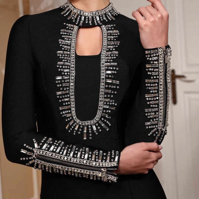 Duga večernja haljina s dugim rukavima, uski kroj, ukrašena perlicama i zatvaračem, materijal poliester-elastan.