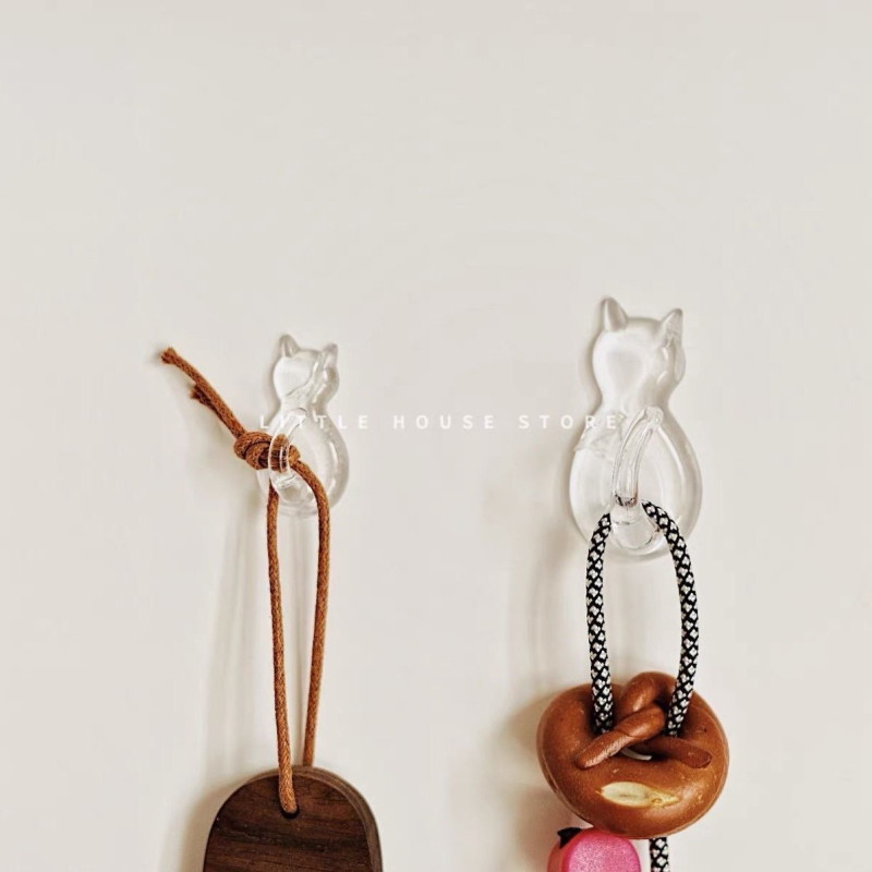 Caurskatāms sveķu kaķa motīva āķis – sienai bez urbšanas, vienkāršs karikatūras stils, maksimālā slodze 0–1 kg, izlaidums 2025