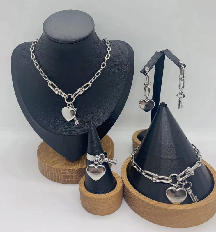 Set de bijuterii din oțel inoxidabil: pandantiv inimă, cheie, lanț în formă de U, brățară și colier; pandantiv din plexiglas; formă feminină; lanț de tip regular; număr de producție N001