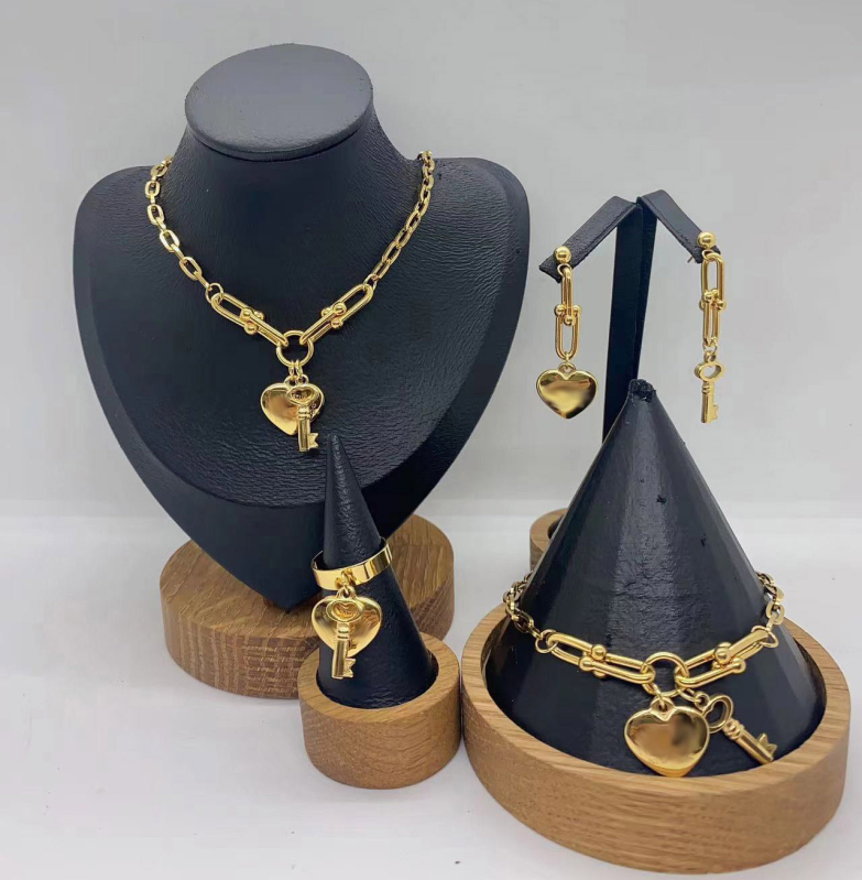 Set de bijuterii din oțel inoxidabil: pandantiv inimă, cheie, lanț în formă de U, brățară și colier; pandantiv din plexiglas; formă feminină; lanț de tip regular; număr de producție N001