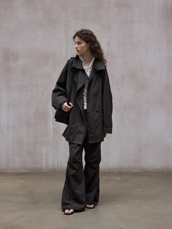 Trench kaput sa stojećim ovratnikom, pamuk-poliester smjesa, jednobojan, udobna silueta, duljina 80–100 cm, jednostruko kopčanje na gumbe.
