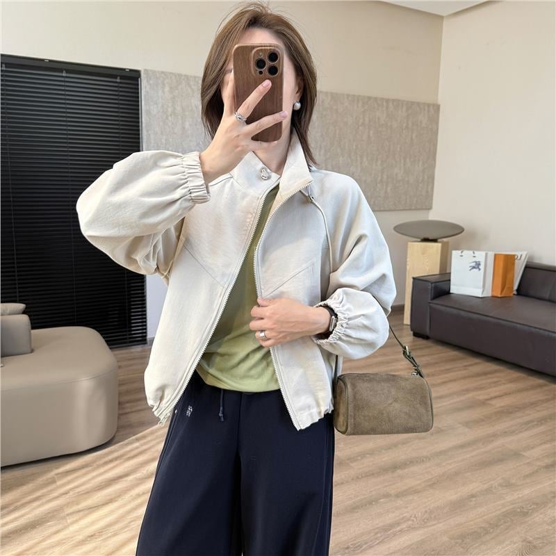 Casual kratka jakna s stojećim ovratnikom i raglan rukavima — poliester 70–80%, jednobojna, duljina 40–50 cm, zatvarač, slobodan kroj