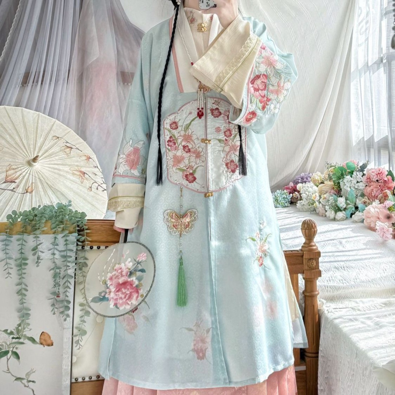 Hanfu szett: hosszú köntös álló gallérral és elöl nyíló felsőrész, hímzett; anyaga poliészter 30–50% regenerált cellulózrosttal; 2024 tavaszi kiadás