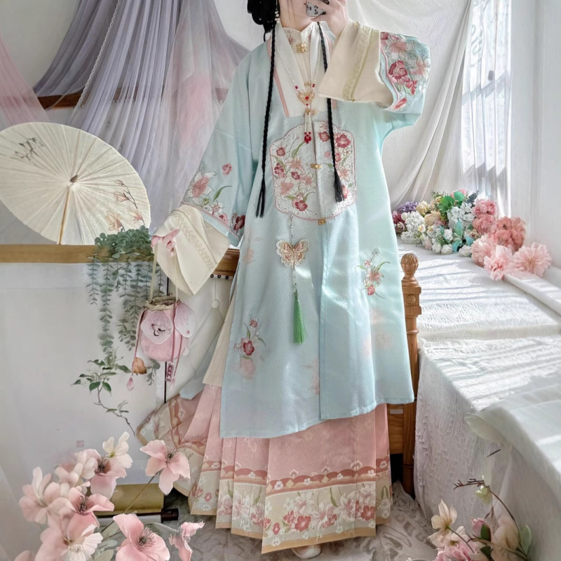 Hanfu szett: hosszú köntös álló gallérral és elöl nyíló felsőrész, hímzett; anyaga poliészter 30–50% regenerált cellulózrosttal; 2024 tavaszi kiadás