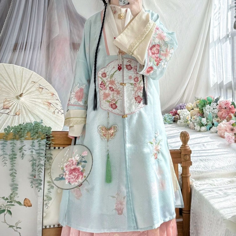 Hanfu szett: hosszú köntös álló gallérral és elöl nyíló felsőrész, hímzett; anyaga poliészter 30–50% regenerált cellulózrosttal; 2024 tavaszi kiadás