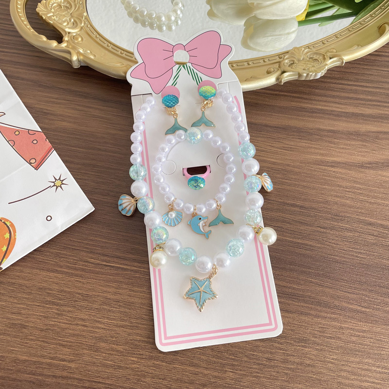 Gyerekeknek tengeri témájú ékszerkészlet: nyaklánc, karkötő, fülbevaló clip és gyűrű csillaghal és kagyló motívummal. Kézzel készített; anyag: műanyag/gyanta; medál anyaga: ötvözet; golyós lánc; többszintű dizájn; hosszabbító 10 cm alatt; Ocean sorozat