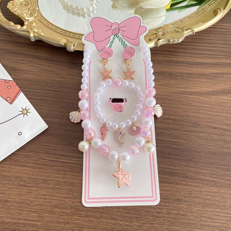 Gyerekeknek tengeri témájú ékszerkészlet: nyaklánc, karkötő, fülbevaló clip és gyűrű csillaghal és kagyló motívummal. Kézzel készített; anyag: műanyag/gyanta; medál anyaga: ötvözet; golyós lánc; többszintű dizájn; hosszabbító 10 cm alatt; Ocean sorozat