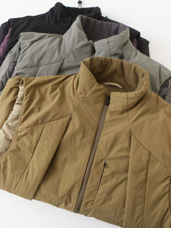 Zimska unisex puffer vesta s stojećim ovratnikom, slobodan kroj, vanjski materijal poliester, punilo poliester, podstava poliester, srednja duljina, bočni džepovi