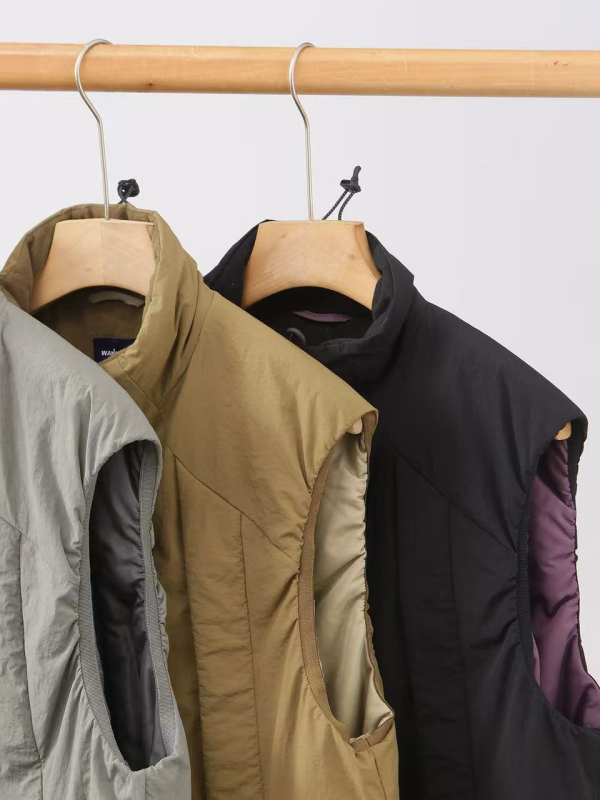 Zimska unisex puffer vesta s stojećim ovratnikom, slobodan kroj, vanjski materijal poliester, punilo poliester, podstava poliester, srednja duljina, bočni džepovi