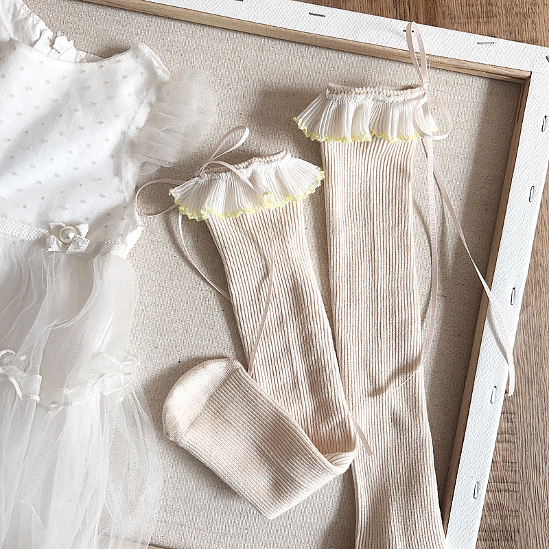 Lastel keskmise pikkusega sokid, käsitöö, pitsiline ääris ja lint, printsess-stiil, kangas, geomeetriline muster, kevad 2025