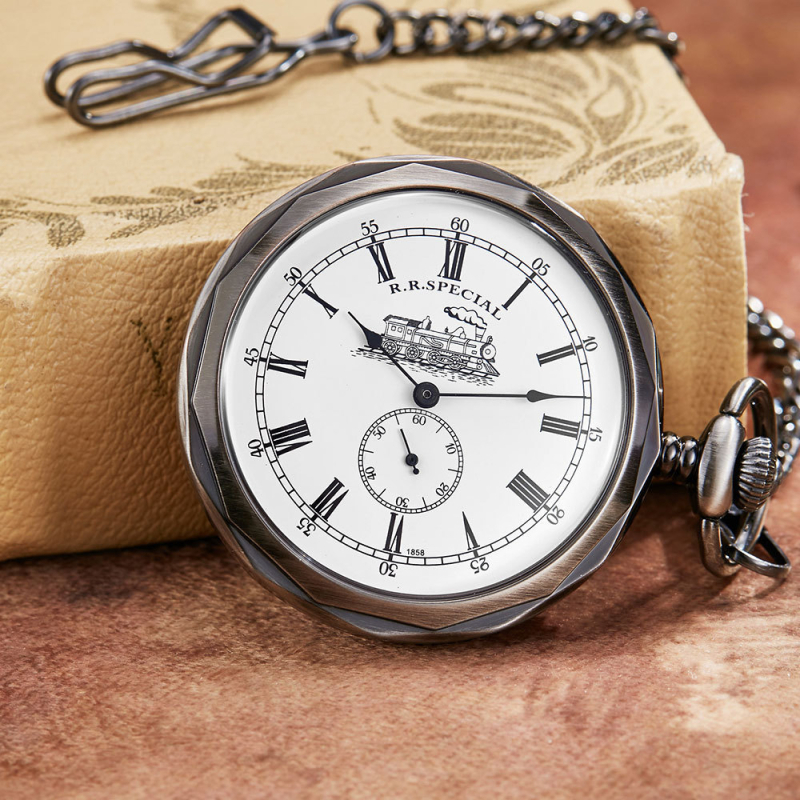 Antikvarinis kišeninis laikrodis su atvira priekine puse, graviruotas traukinių motyvas, skaidrus galinis dangtelis, rankinis mechaninis judėjimas, lydinio korpusas