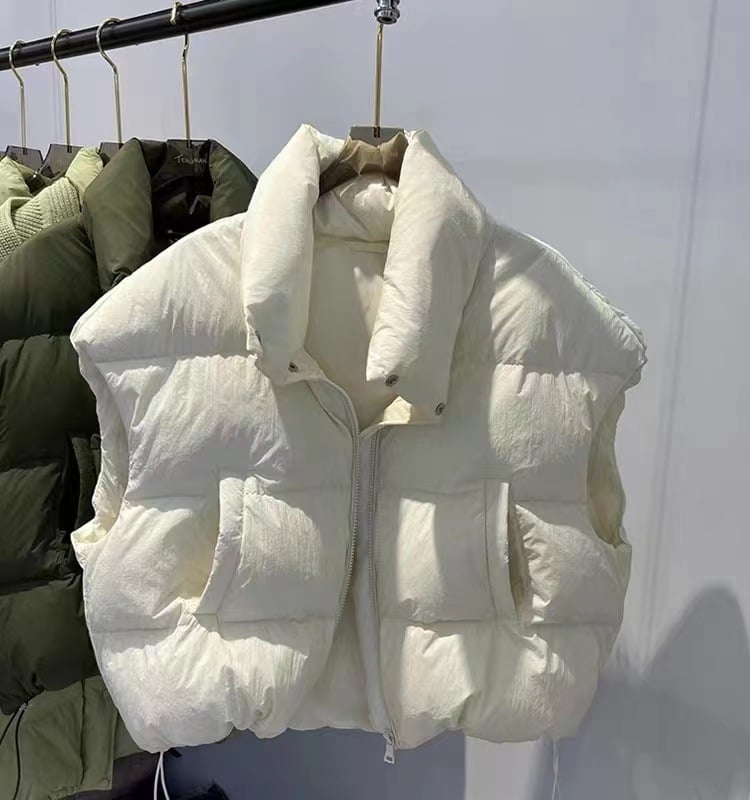 Naistele mõeldud lühike vatiinist vest, seisev krae ja tõmblukk — väline materjal: polüester, täidis: puuvill, pikkus 50–65 cm