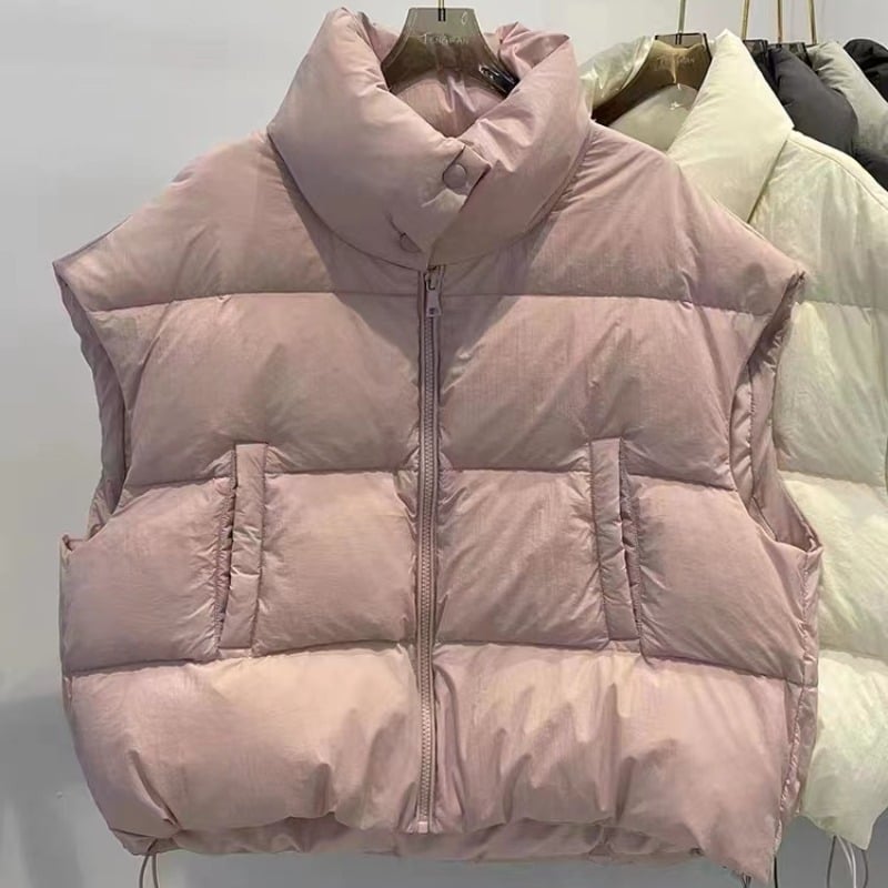 Naistele mõeldud lühike vatiinist vest, seisev krae ja tõmblukk — väline materjal: polüester, täidis: puuvill, pikkus 50–65 cm