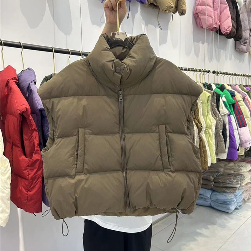 Naistele mõeldud lühike vatiinist vest, seisev krae ja tõmblukk — väline materjal: polüester, täidis: puuvill, pikkus 50–65 cm