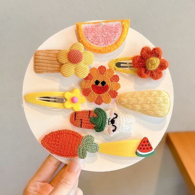 Lastele mõeldud juukseaksessuaaride komplekt — käsitöö kõrval klips lillmotiiviga joonistusstiilis, vanuserühm 3–10 aastat.