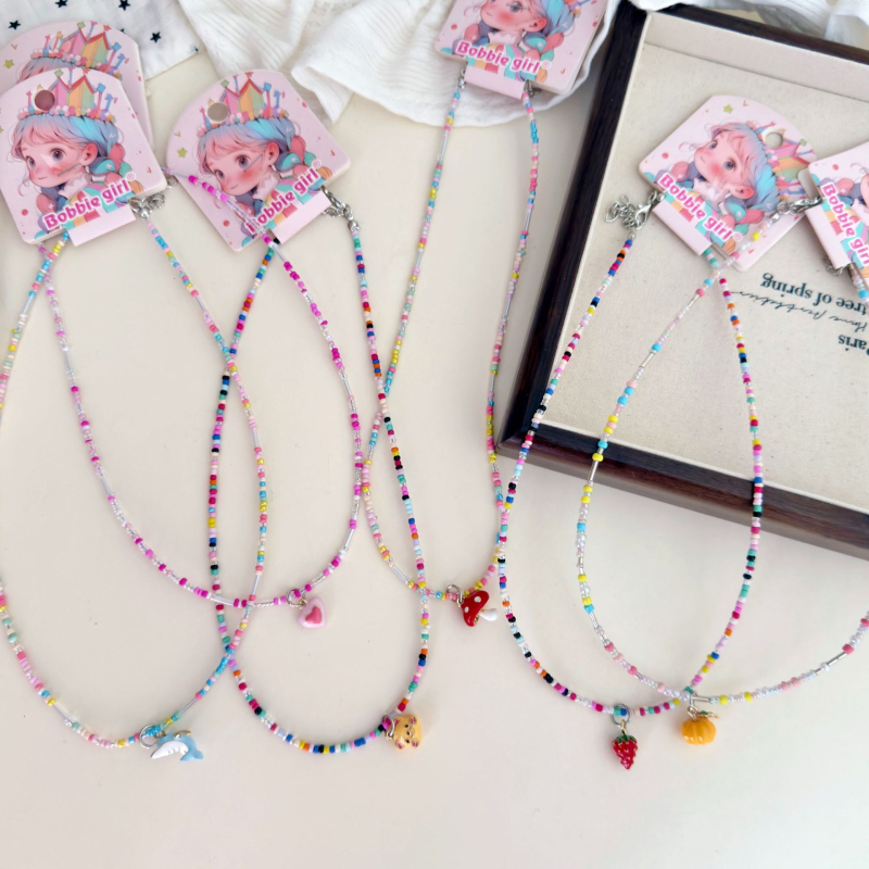 Bērnu kaklarota ar pērļu motīviem – augļu un dzīvnieku motīvi; adīta ar rokām, plastmasa/sveķi; bērnu stils, vasara 2025