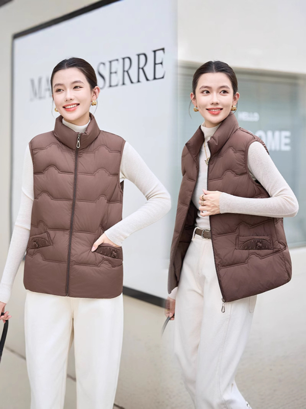 Sieviešu veste ar stāvošu apkakli; tievs piegriezums; īss garums 40–50 cm; rāvējslēdzējs; poliestera audums