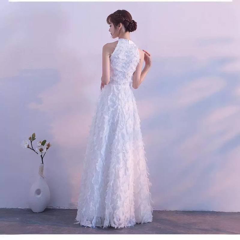 Balta plunksnų apdaila su atvirais pečiais, ilga vakarinė suknelė su aukštu liemeniu, skirta baigimui ir choro pasirodymams