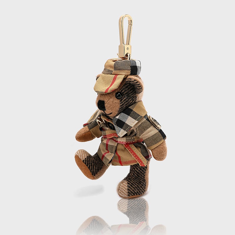 Lācīša formā plīša kulons somām; kašmīra materiāls ar metāla pārklājumu; oriģinālais dizains, piemiņas stilā; uzraksts ar lāci un maziem dzīvniekiem; karu tekstūra