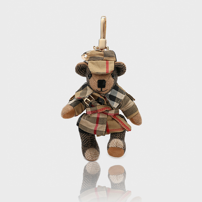 Lācīša formā plīša kulons somām; kašmīra materiāls ar metāla pārklājumu; oriģinālais dizains, piemiņas stilā; uzraksts ar lāci un maziem dzīvniekiem; karu tekstūra