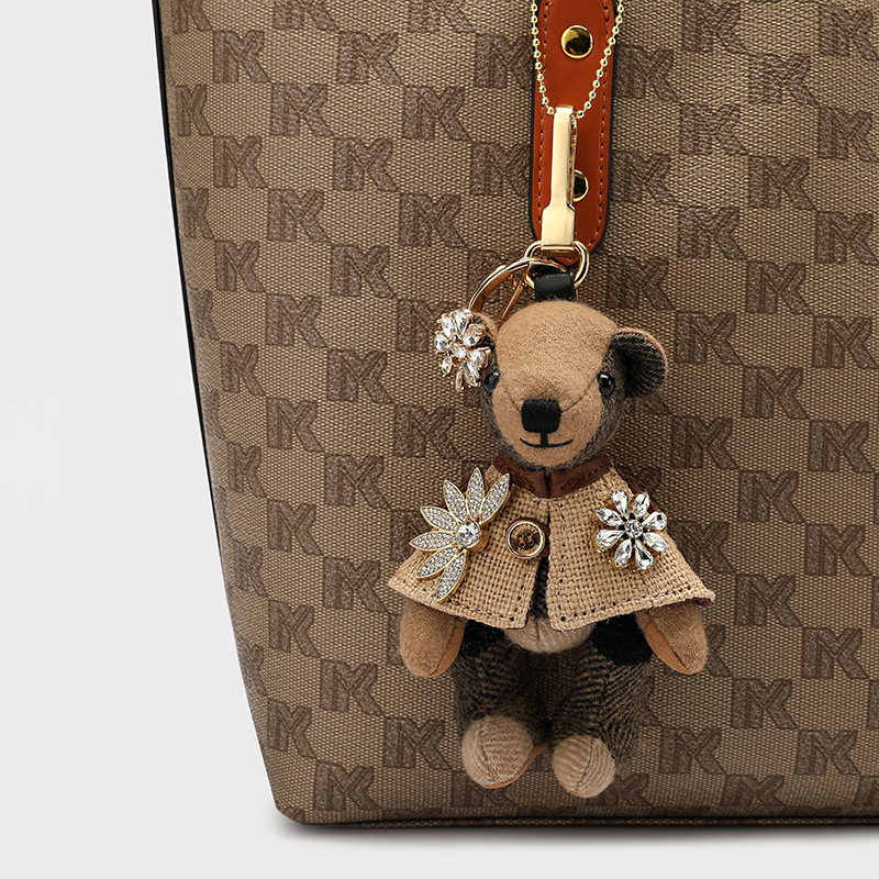 Lācīša formā plīša kulons somām; kašmīra materiāls ar metāla pārklājumu; oriģinālais dizains, piemiņas stilā; uzraksts ar lāci un maziem dzīvniekiem; karu tekstūra