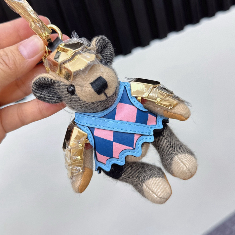 Lācīša formā plīša kulons somām; kašmīra materiāls ar metāla pārklājumu; oriģinālais dizains, piemiņas stilā; uzraksts ar lāci un maziem dzīvniekiem; karu tekstūra