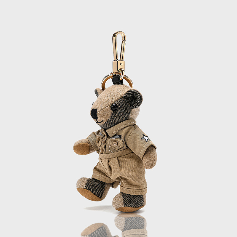 Lācīša formā plīša kulons somām; kašmīra materiāls ar metāla pārklājumu; oriģinālais dizains, piemiņas stilā; uzraksts ar lāci un maziem dzīvniekiem; karu tekstūra