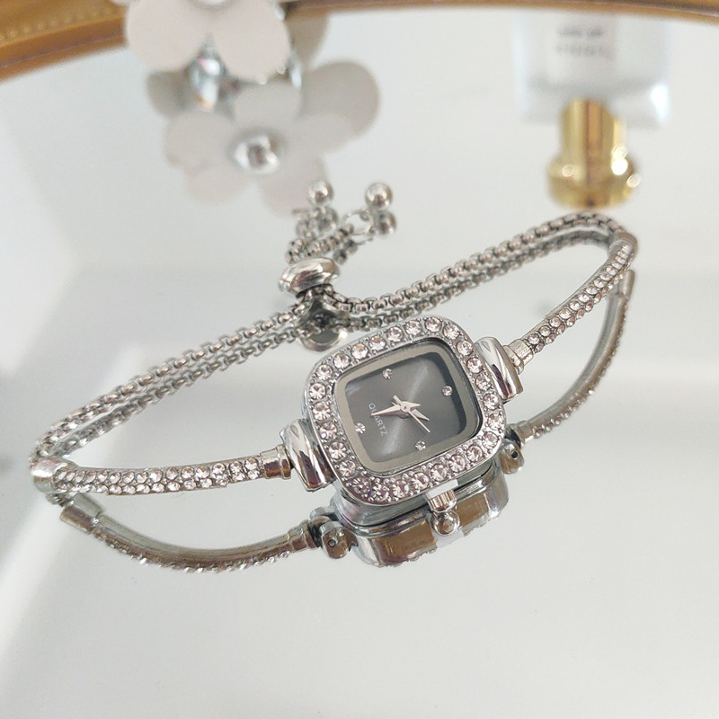 Ženski kvarcni sat s dekorativnim kamenčićima i svjetskim vremenom; metalno kućište i kaiš, okrugli brojčanik, leptir kopča