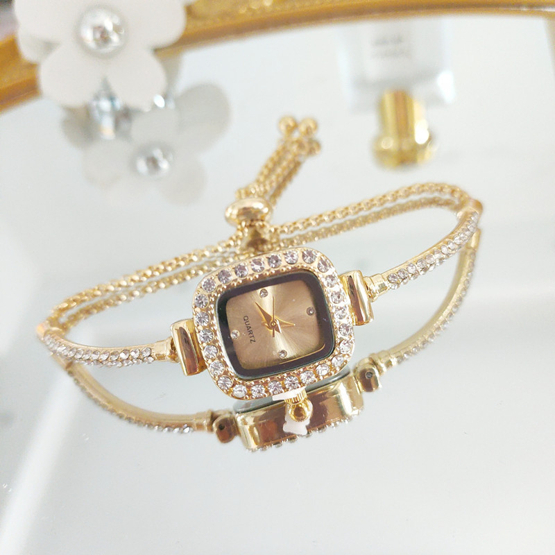 Ženski kvarcni sat s dekorativnim kamenčićima i svjetskim vremenom; metalno kućište i kaiš, okrugli brojčanik, leptir kopča