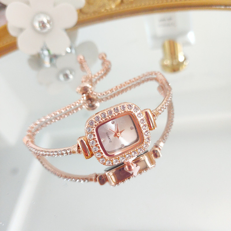 Ženski kvarcni sat s dekorativnim kamenčićima i svjetskim vremenom; metalno kućište i kaiš, okrugli brojčanik, leptir kopča