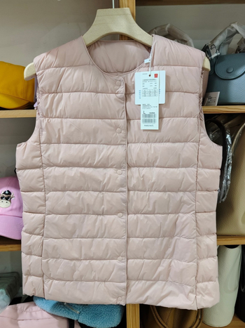 Sieviešu dūnu pildīta veste, vidēja biezuma, poliestera audums, kašmīrs 81–85%, garums 50–65 cm, apaļš kakla izgriezums, vienpogu aizdare, standarta griezums