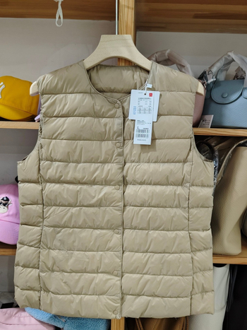 Sieviešu dūnu pildīta veste, vidēja biezuma, poliestera audums, kašmīrs 81–85%, garums 50–65 cm, apaļš kakla izgriezums, vienpogu aizdare, standarta griezums