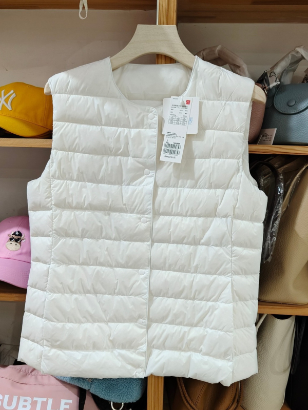 Sieviešu dūnu pildīta veste, vidēja biezuma, poliestera audums, kašmīrs 81–85%, garums 50–65 cm, apaļš kakla izgriezums, vienpogu aizdare, standarta griezums