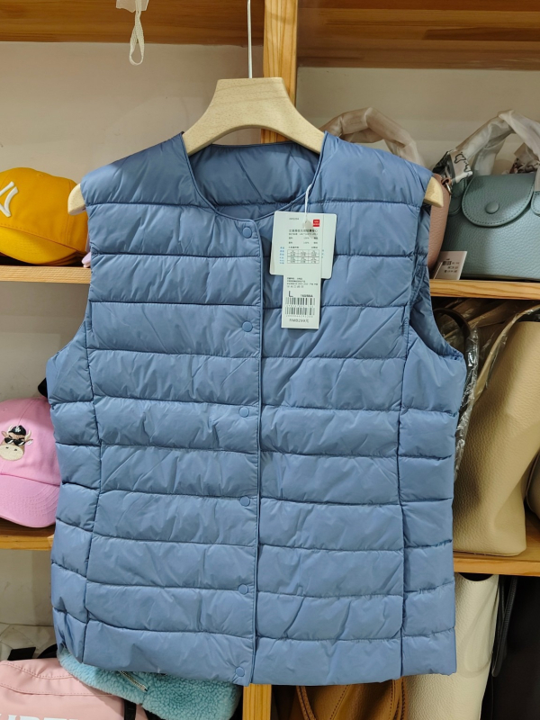 Sieviešu dūnu pildīta veste, vidēja biezuma, poliestera audums, kašmīrs 81–85%, garums 50–65 cm, apaļš kakla izgriezums, vienpogu aizdare, standarta griezums