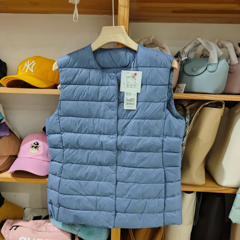 Sieviešu dūnu pildīta veste, vidēja biezuma, poliestera audums, kašmīrs 81–85%, garums 50–65 cm, apaļš kakla izgriezums, vienpogu aizdare, standarta griezums