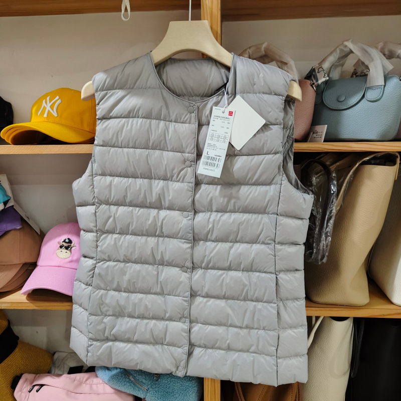 Sieviešu dūnu pildīta veste, vidēja biezuma, poliestera audums, kašmīrs 81–85%, garums 50–65 cm, apaļš kakla izgriezums, vienpogu aizdare, standarta griezums