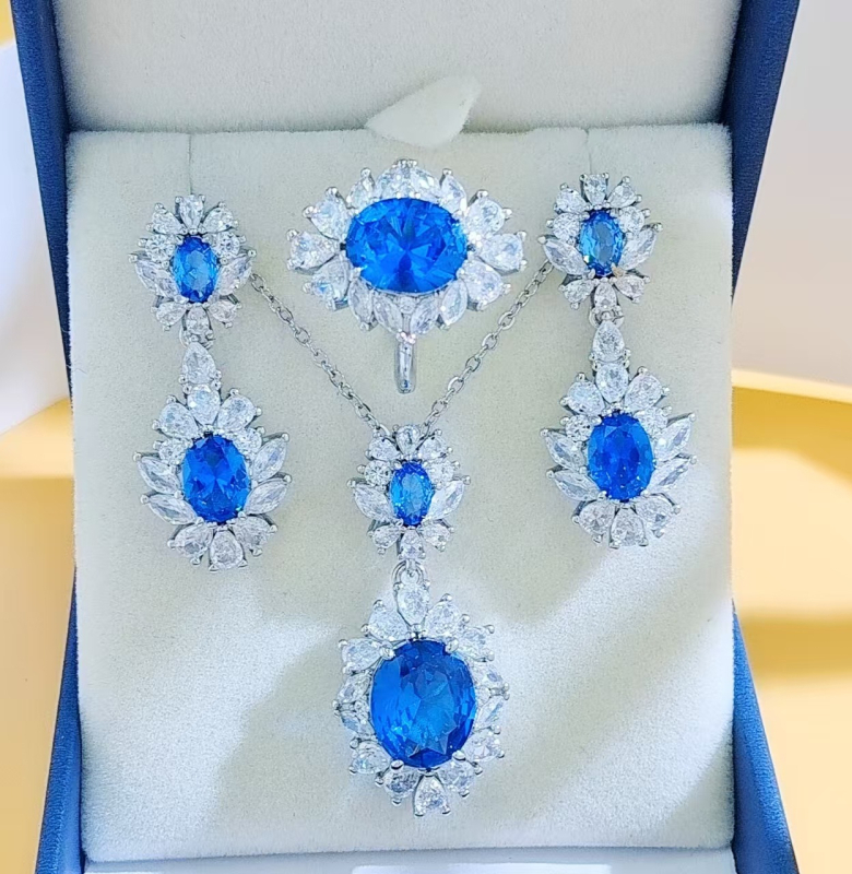 Virágos három darabos ékszerszett: gyűrű, nyaklánc, fülbevaló; alap bevonattal; betoldott szintetikus kövekkel; O alakú lánc; virág motívum