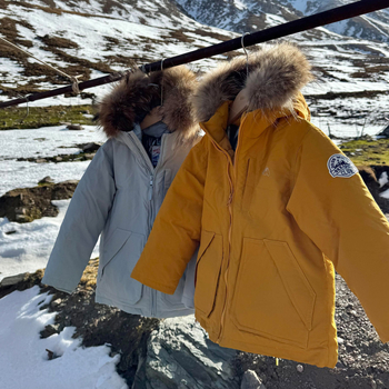 Meitenēm paredzēta pūkaina jaka ar kapuci – ar augstu apkakli, biezu pildījumu, 81–85% pīļu pūka, īss siluets