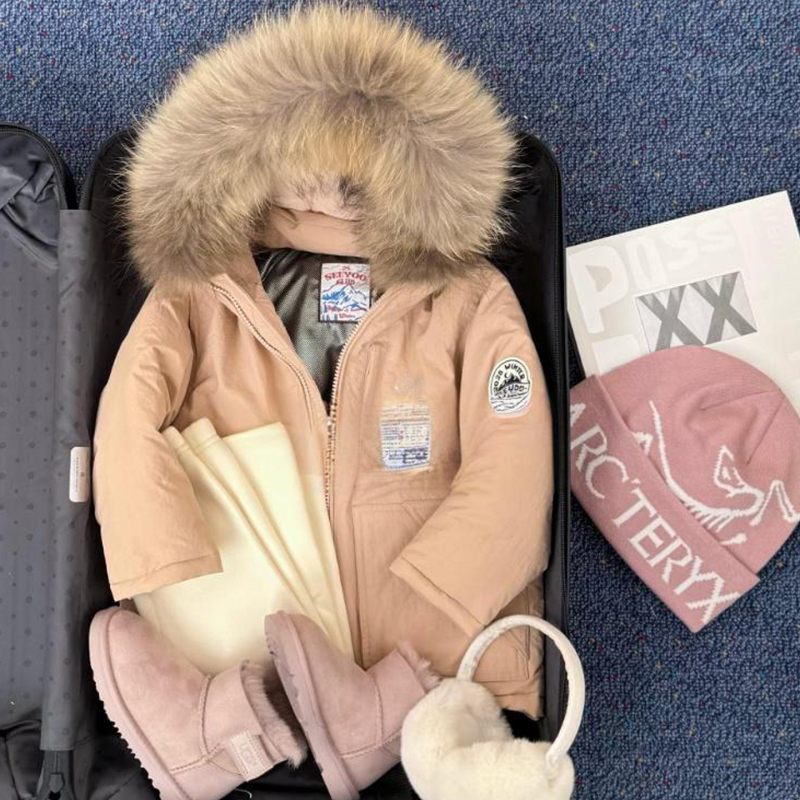 Meitenēm paredzēta pūkaina jaka ar kapuci – ar augstu apkakli, biezu pildījumu, 81–85% pīļu pūka, īss siluets