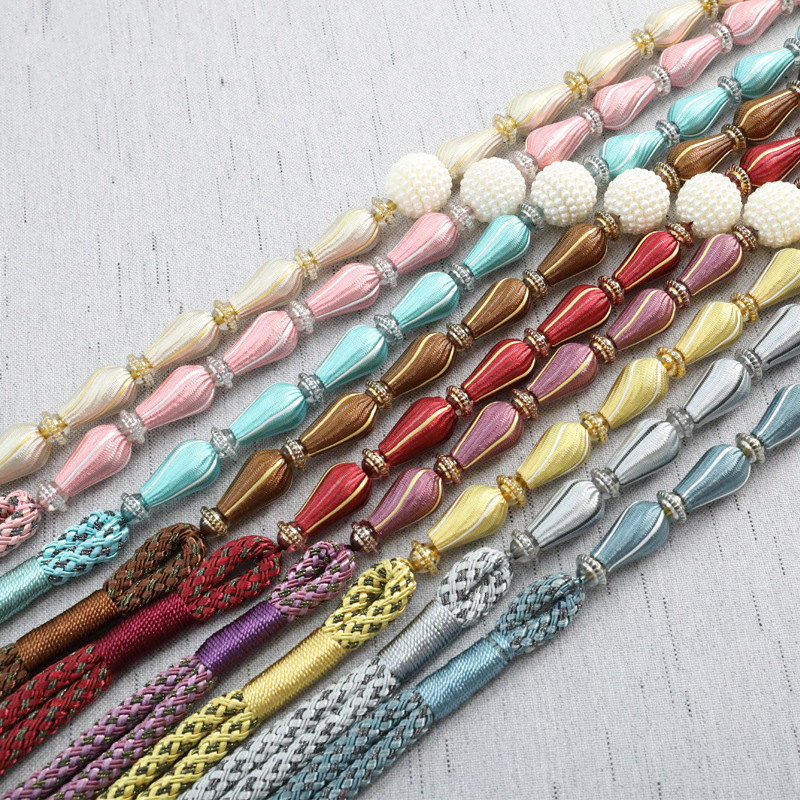 Aizkaru aizdare komplekts ar karājošu bumbiņu, pērles, sprādzi, auklu un uzglabāšanas jostu – gaišs luksusa stils